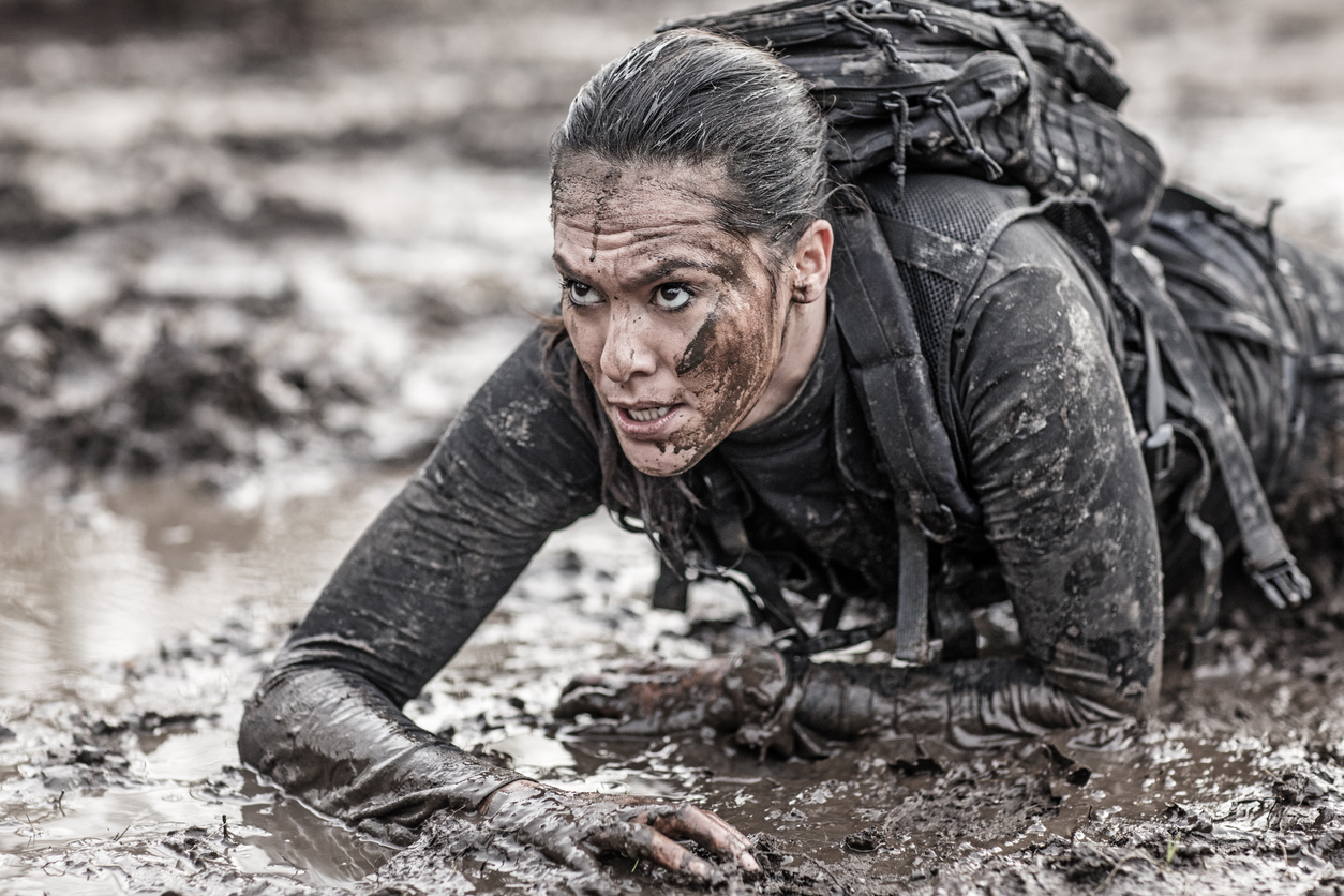 Beautiful brunette female military swat security anti terror agent crawling during operations in muddy sand